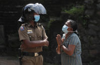 A family member of an inmate pleads to a policeman as she seeks information on the condition of her relative outside the Mahara prison complex following an overnight unrest in Mahara, outskirts of Colombo, Sri Lanka, Monday, Nov. 30, 2020. Sri Lankan officials say six inmates were killed and 35 others were injured when guards opened fire to control a riot at a prison on the outskirts of the capital. Two guards were critically injured. Pandemic-related unrest has been growing in Sri Lanka's overcrowded prisons. (AP Photo/Eranga Jayawardena)