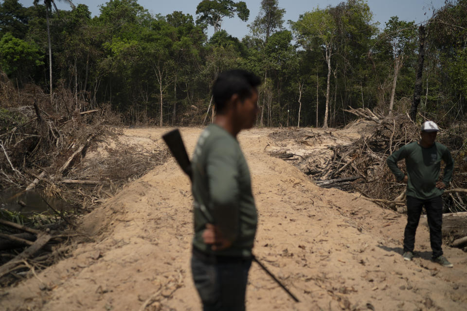 FILE - In this Aug. 31, 2019 file photo, Monhire Menkragnotire, of the Kayapo indigenous community, center, surveys an area where illegal loggers opened a 8km road to enter Menkragnotire indigenous lands, where logging is illegal, on the border with the Biological Reserve Serra do Cachimbo, top, where logging is also illegal, in Altamira, Para state, Brazil. Documents seen by The Associated Press show that Brazil's government has begun legal procedures to shut down three of the state’s four environmental protection offices that belong to the government’s Brazilian Institute of the Environment and Renewable Natural Resources, or Ibama, in charge of defending the country’s forests from illegal deforestation, land grabbing, or fires. (AP Photo/Leo Correa, File)