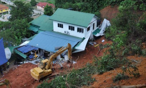 Emergency teams work to clear the damage created by a landslide that destroyed an orphanage in the Malaysian province of Hulu Langat. A close-knit village on the outskirts of the Malaysian capital was grieving for the deaths of 16 people, mostly children, after an orphanage was hit by a devastating landslide