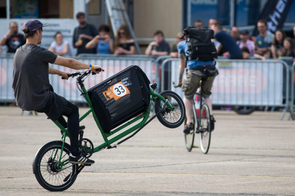 A man pulls a wheelie on a green cargo bike