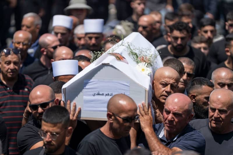 People mourn at the funeral of their relatives in the Druze town of Majd al-Shams in the Israeli-controlled Golan Heights. Several children and young people were killed in a rocket attack on a football field in the village. Ilia Yefimovich/dpa