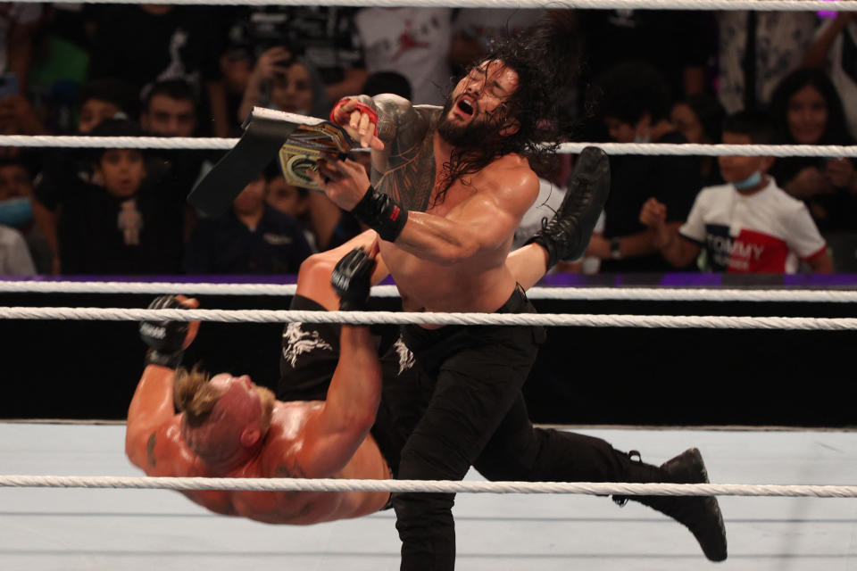 Roman Reigns golpea a Brock Lesnar con el Campeonato Universal durante WWE Crown Jewel 2021. (Fayez Nureldine/AFP v&#xed;a Getty Images)