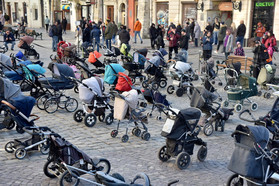 People look at 109 empty prams placed in the center of Lviv during the 