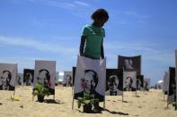 A girl stands next to posters of former South African President Nelson Mandela displayed on the Copacabana beach by non-governmental organization (NGO) "Rio de Paz" (Rio of Peace) to honour Mandela before his burial, in Rio de Janeiro December 14, 2013. Mandela will be buried on Sunday in Qunu, his ancestral home in the rolling hills of the Eastern Cape province, 900 km (559 miles) south of Johannesburg. REUTERS/Pilar Olivares (BRAZIL - Tags: POLITICS OBITUARY TPX IMAGES OF THE DAY)