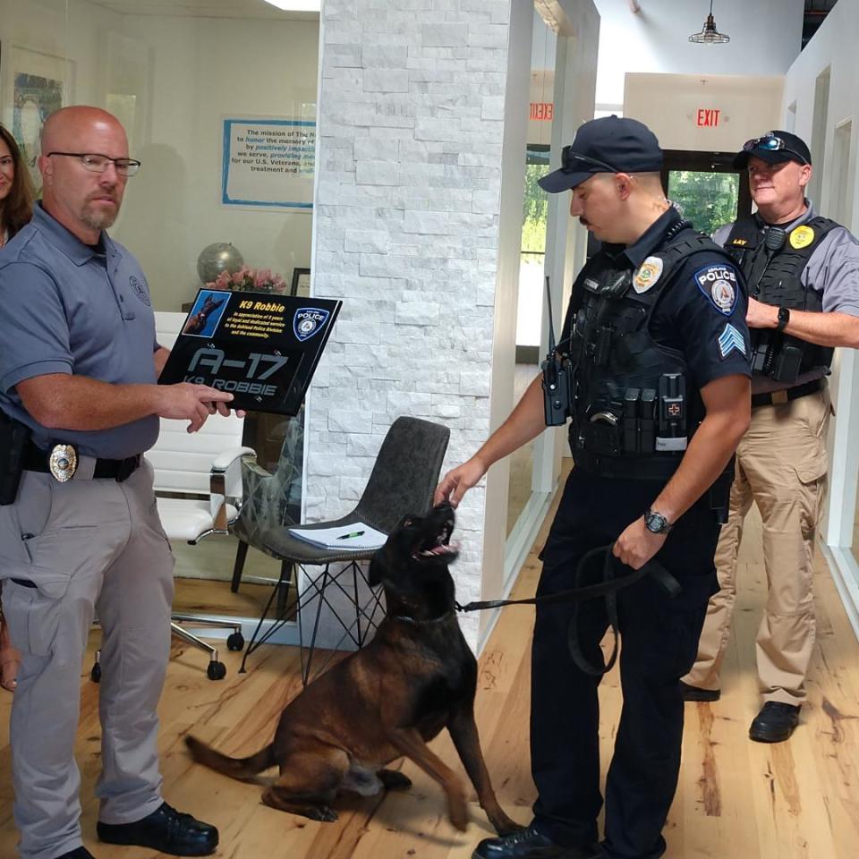 Capt. Craig Kiley presents a plaque to Sgt. Tim Atchison and his retiring K9 Robbie. Chief David Lay is in the background.