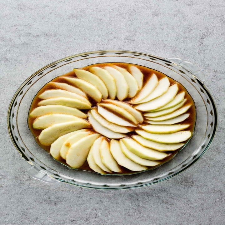 uncooked apples layered over a caramel sauce in a dish