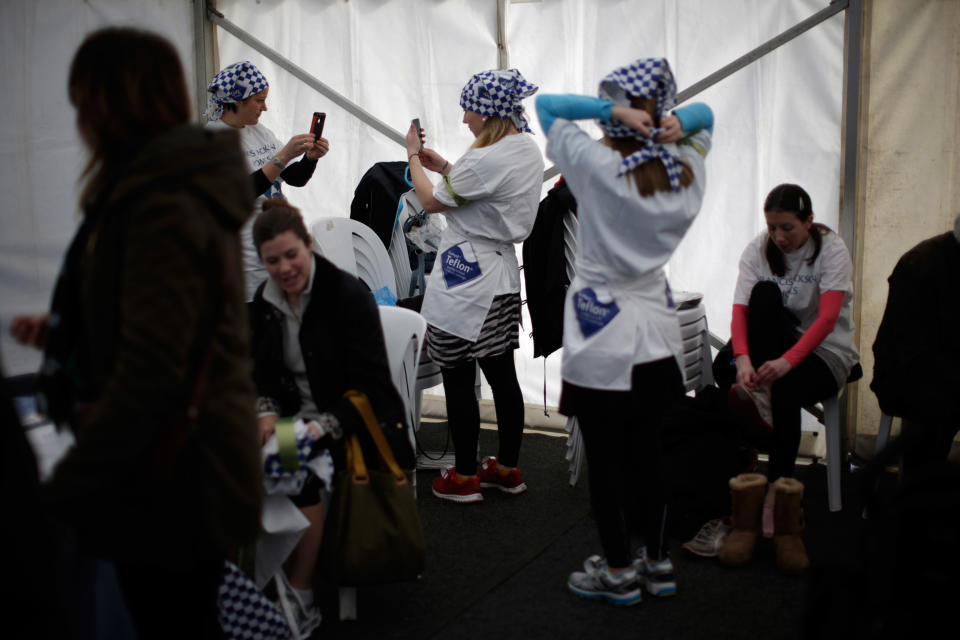 Participants get ready before the start of the annual Shrove Tuesday trans-Atlantic pancake race, in the town of Olney, in Buckinghamshire, England, Tuesday, March 4, 2014. Every year women clad in aprons and head scarves from Olney and the city of Liberal, in Kansas, USA, run their respective legs of the race with a pancake in their pan, flipping it at the beginning and end of the race. According to legend, the Olney race started in 1445 when a harried housewife arrived at church on Shrove Tuesday still clutching her frying pan with a pancake in it. Liberal challenged Olney to a friendly international competition in 1950 after seeing photos of the race in a magazine. (AP Photo/Matt Dunham)