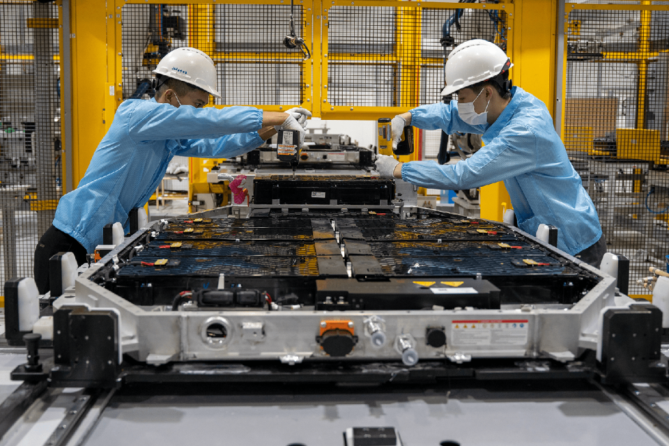 a couple of men wearing hard hats working on a machine