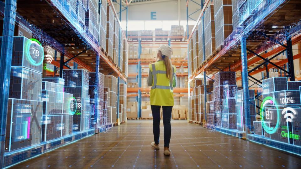 A person walking through a factory between two digitally-enhanced shelves.