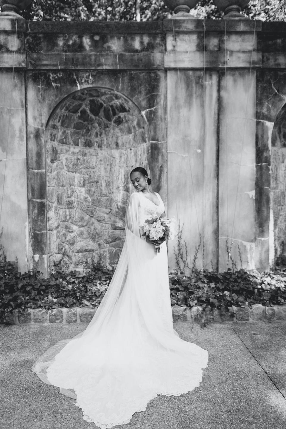 A bride poses in her wedding dress in a black and white photo.