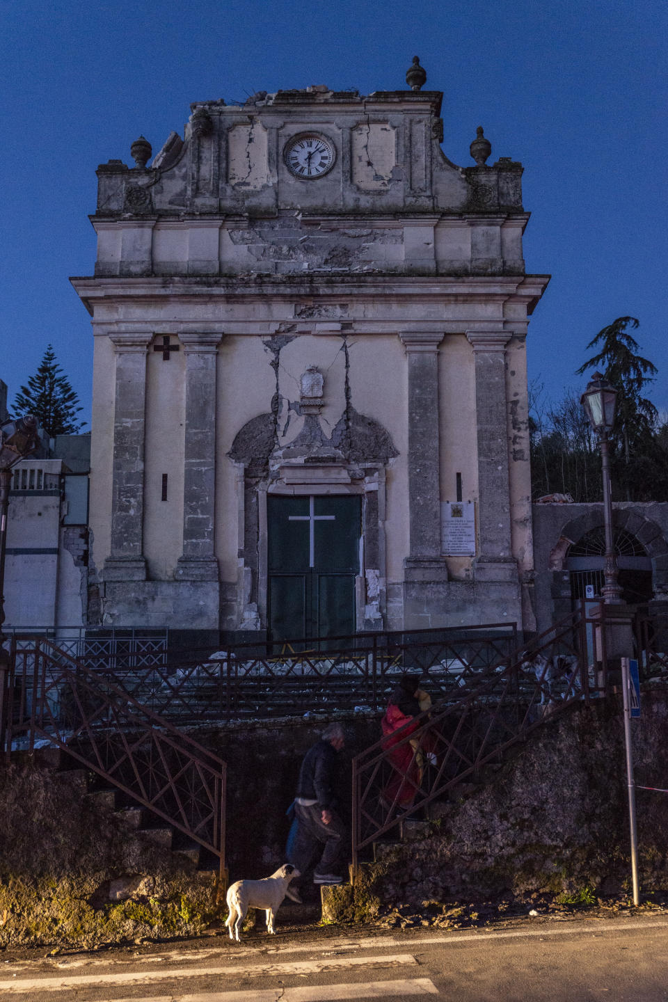 People walk in front of the heavily damaged church of Maria Santissima in Fleri, Sicily Italy, Wednesday, Dec. 26, 2018. A quake triggered by Italy's Mount Etna volcano has jolted eastern Sicily, slightly injuring 10 people and prompting frightened Italian villagers to flee their homes. (AP Photo/Salvatore Allegra)