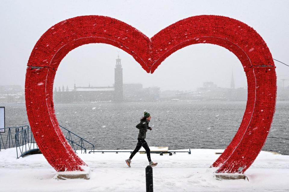 A jogger runs past a sculpture resembling a heart during snowfall in Stockholm, Sweden (TT News Agency/AFP via Getty Ima)