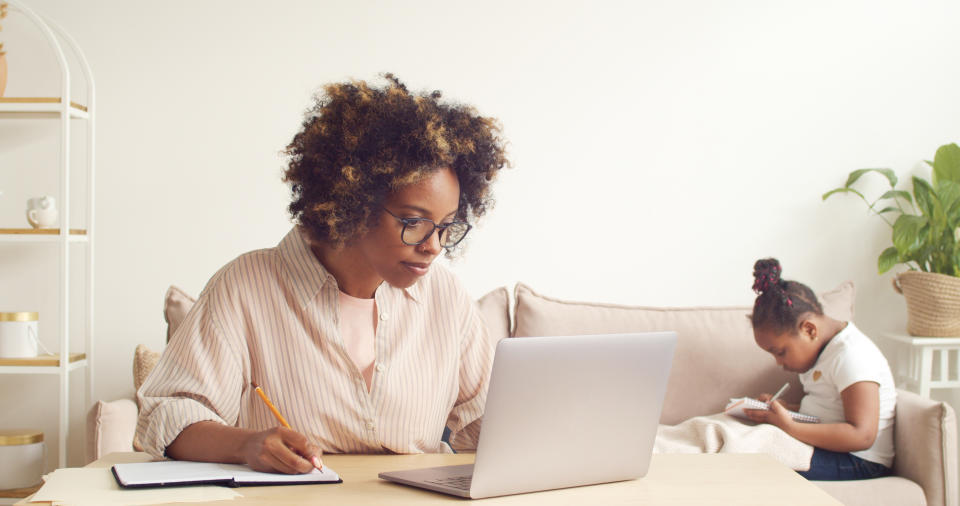 tax Single mom working at home online with her child on couch while writing. Remote office concept