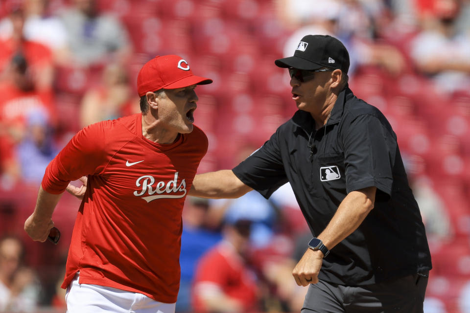 Cincinnati Reds' David Bell, left, is restrained by umpire Andy Fletcher as he yells towards umpire Gerry Davis during the ninth inning of a baseball game against the Tampa Bay Rays in Cincinnati, Wednesday, April 19, 2023. The Rays won 8-0. (AP Photo/Aaron Doster)