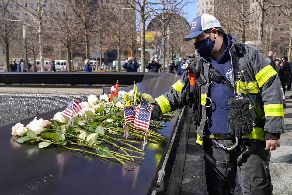 A firefighter places a rose next to the names of the victims of the 1993 bombing of the World Trade Center during a ceremony marking the 28th anniversary of the attack, Friday, Feb. 26, 2021, in New York. On Feb. 26, 1993, a truck bomb built by Islamic extremists exploded in the parking garage of the North Tower of the World Trade Center, killing six people and injuring more than 1,000 others. (AP Photo/Mary Altaffer)