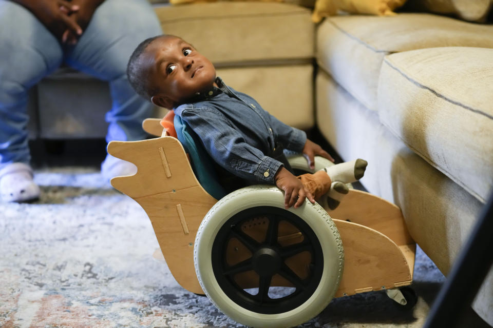 Elijah Jack, 1, looks up from his mobility chair, which was built as a donation by Tulane University students, at his home in New Roads, La., Thursday, Nov. 30, 2023. Tulane science and engineering students are making the second batch of mobility chairs for toddlers, that will eventually go to pediatric patients at Children's Hospital. Wheelchairs are expensive, and insurance won't cover the cost for children unless the child proves they can operate it independently. (AP Photo/Gerald Herbert)