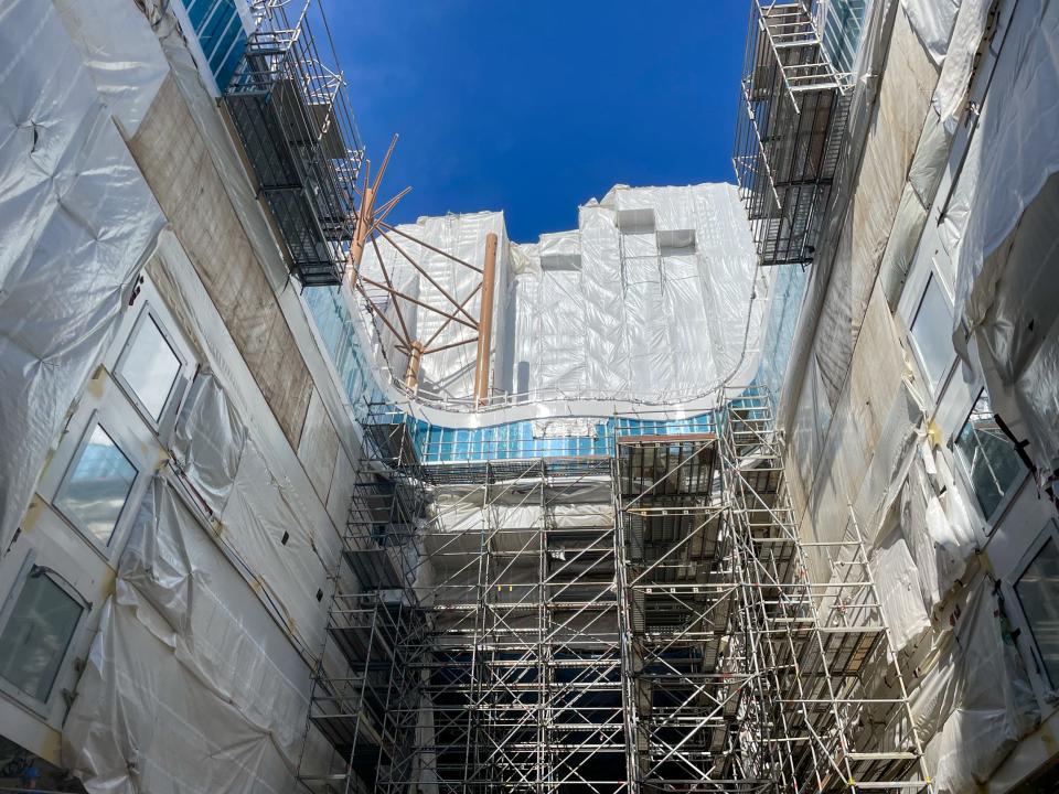 An outdoor space under construction in  Royal Caribbean's Icon of the Seas. It's empty with scaffolding and tarp everywhere