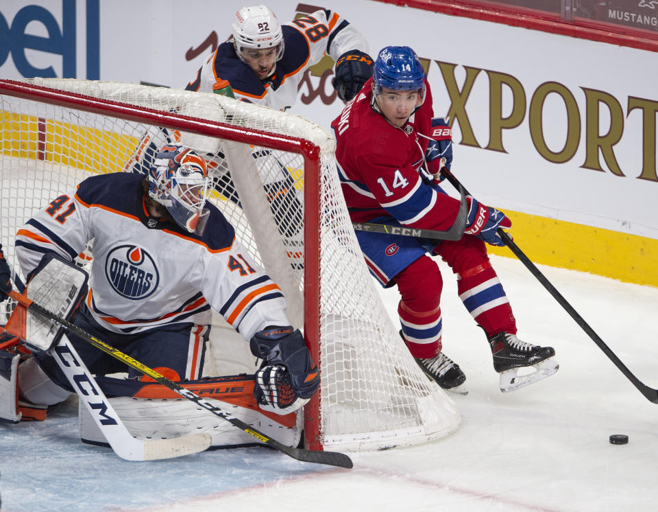 Montreal Canadiens' Nick Suzuki (14) is chased by Edmonton Oilers' Caleb Jones (82) as he tries a wrap around on Oilers goaltender Mike Smith (41) during the second period of an NHL hockey game, Wednesday, May 12, 2021 in Montreal. (Ryan Remiorz/Canadian Press via AP)