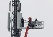 FILE PHOTO: Technicians work at the top of transmitting antennas are seen on a mobile-phone network relay mast in Lambres-lez-Douai