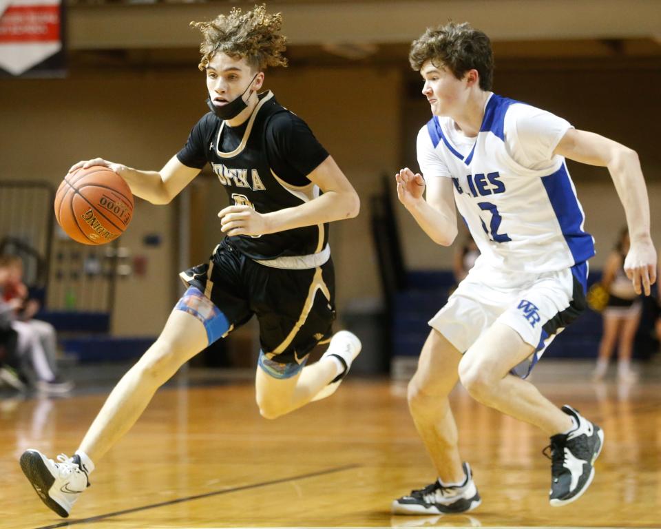 Topeka High sophomore Bryson Thrasher (0) drives past Washburn Rural junior Jack Bachelor (12) Tuesday.