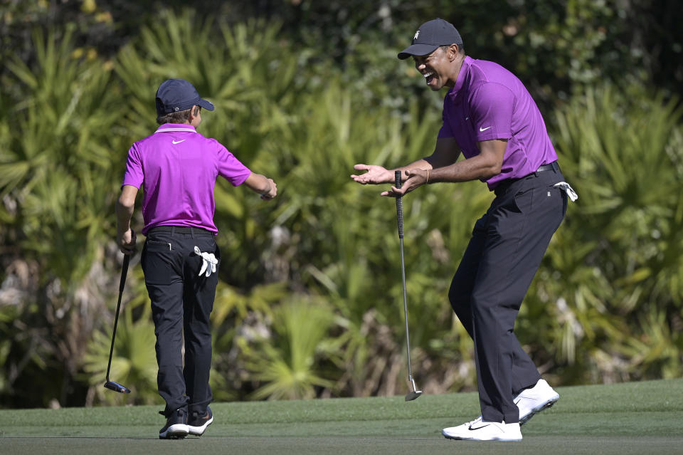 Tiger Woods, right, reacts after his son Charlie sank a putt on the third green during the first round of the PNC Championship golf tournament, Saturday, Dec. 19, 2020, in Orlando, Fla. (AP Photo/Phelan M. Ebenhack)