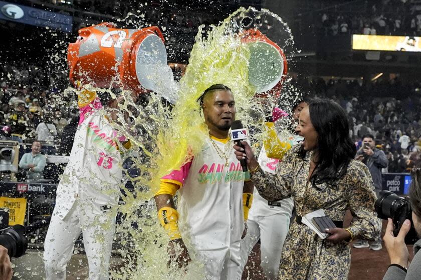 San Diego Padres' Luis Arraez is doused by teammates Manny Machado, left, and Fernando Tatis Jr.