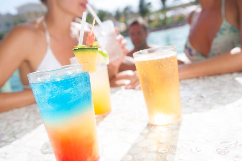 Friends relaxing in pool with cocktails - stock photo