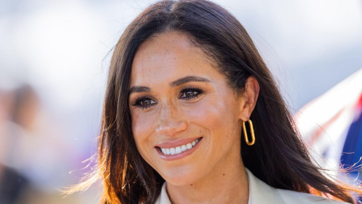 The Duchess of Sussex smiling with gold hoop earrings