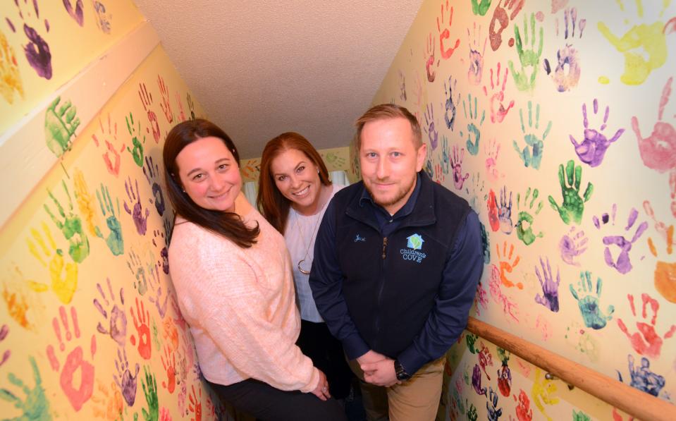 Beth Mitchell, left, Deputy Director, Stacy Gallagher, Director, and Jacob Stapledon, Community Engagement and Education Program Manager, in a decorated stairway at the Cape and Islands Child Advocacy Center, Children's Cove.