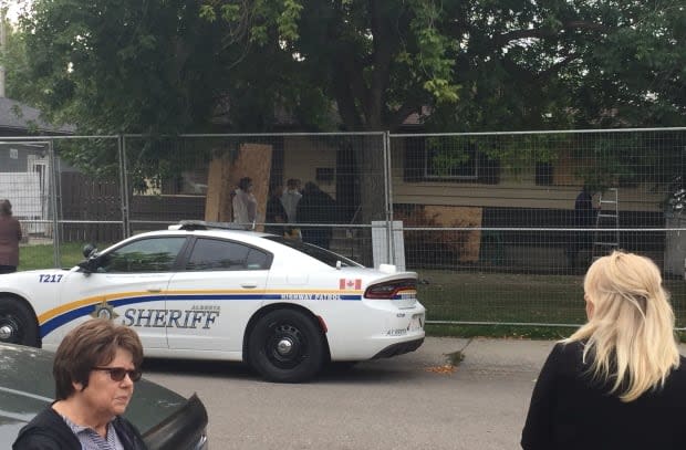 Neighbours watch as provincial sheriffs close down 2000 Cottonwood Crescent S.E. It's been shut a record three times now by the SCAN team. (Seth Barlow - image credit)