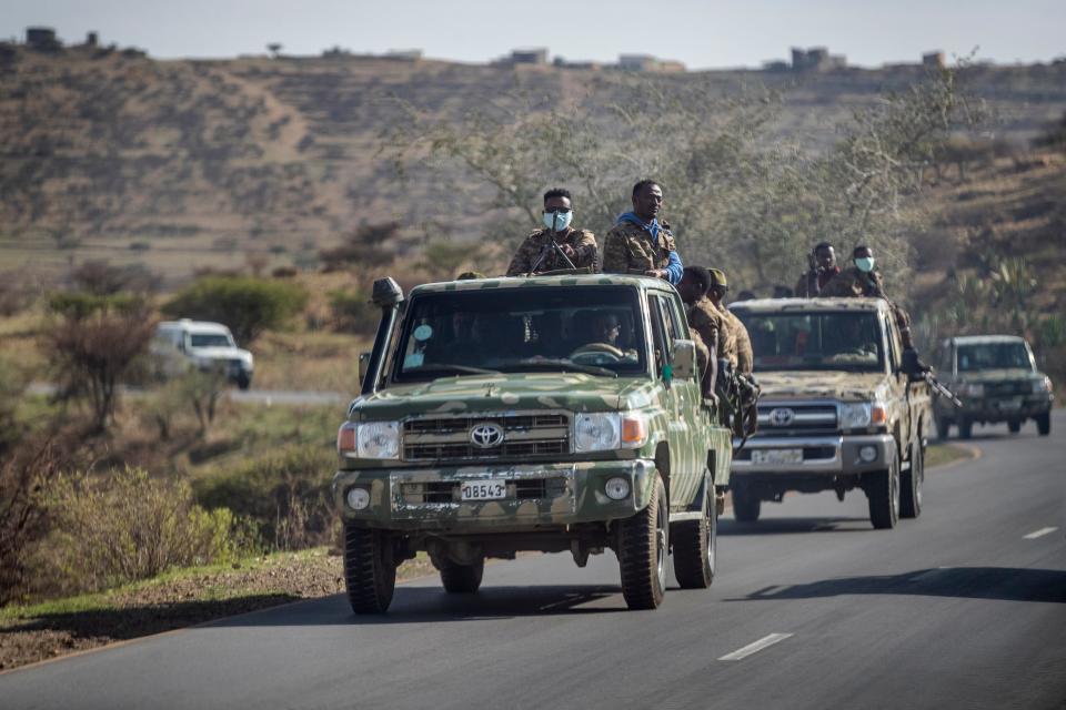 Soldiers are seen riding on trucks.