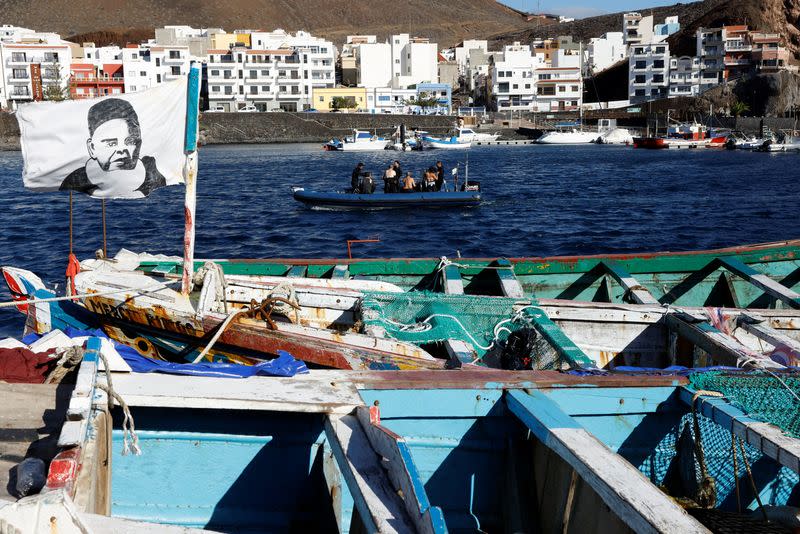 Tourist divers use an inflatable boat near several abandoned wooden boats used by immigrants in the port of La Restinga.