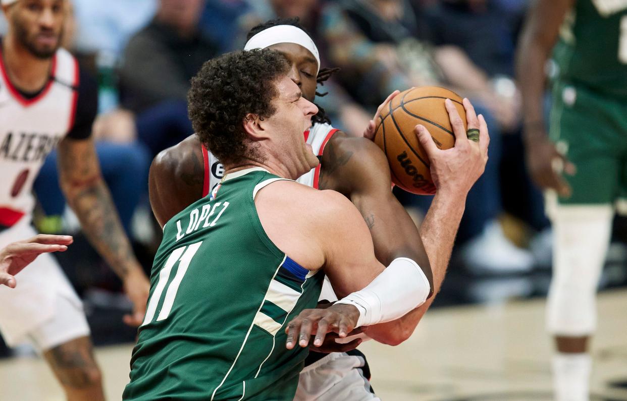 Milwaukee Bucks center Brook Lopez gets hacked across the arms by Portland Trail Blazers forward Jerami Grant as he goes up for a shot during the second half Monday night.