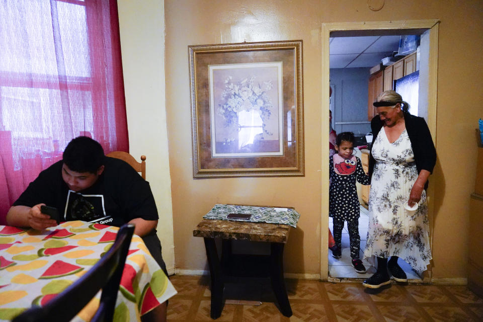 Amanda Brebe, 75, walks with her granddaughter Zuniga Gonzales, 7, as Erick Zuniga Gonzales, 17, sits at the dining room table the Kensington section of Philadelphia, Sunday, May 16, 2021. The family is trying to rebuild their lives together after they were separated under a former “zero-tolerance” policy to criminally prosecute adults who entered the country illegally. (AP Photo/Matt Rourke)
