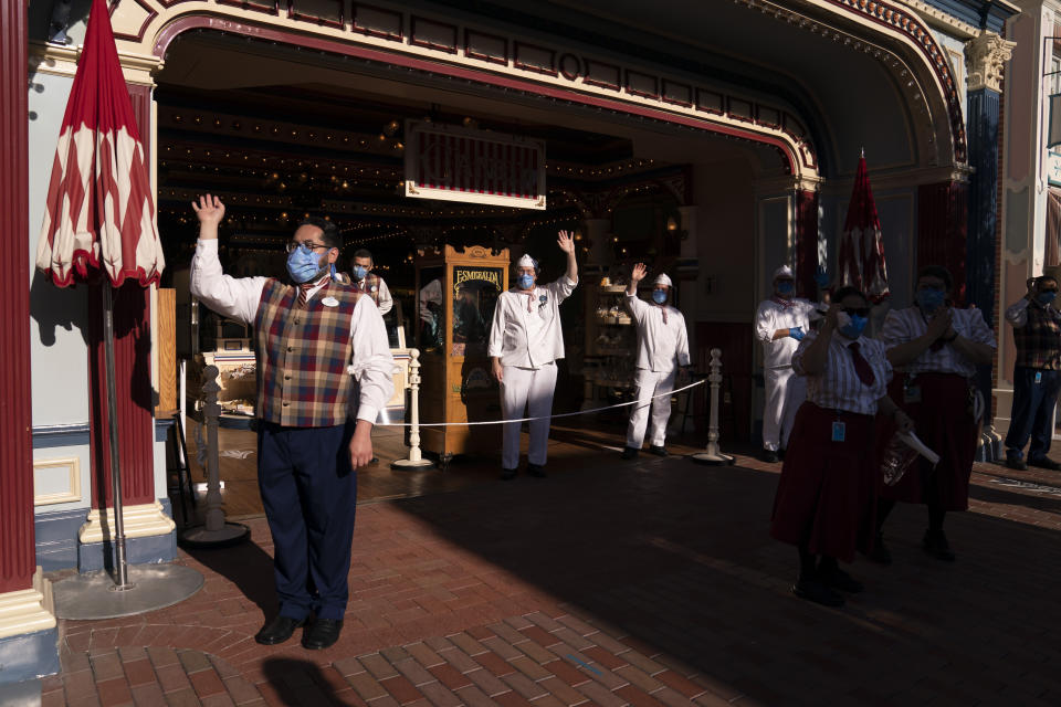 Employees wave as guests walk along Main Street USA at Disneyland in Anaheim, Calif., Friday, April 30, 2021. The iconic theme park in Southern California that was closed under the state's strict virus rules swung open its gates Friday and some visitors came in cheering and screaming with happiness. (AP Photo/Jae C. Hong)