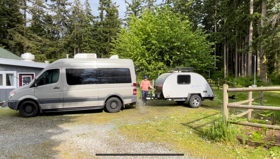 The author's husband washes their Sprinter van and travel trailer for the next renter on Outdoorsy.