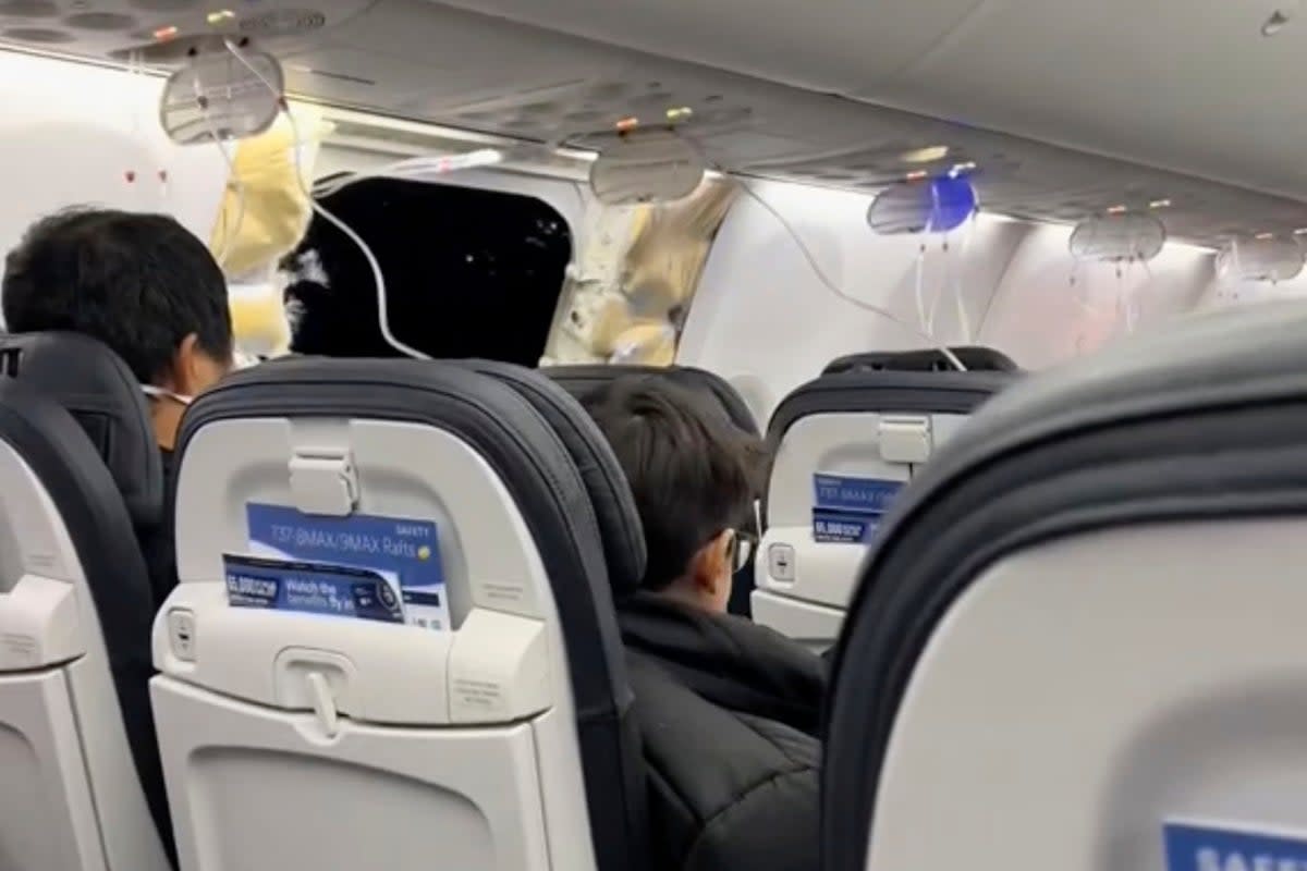 This image from video provided by Elizabeth Le shows passengers near the damage on an Alaska Airlines Boeing 737 Max 9, Flight 1282, which was forced to return to Portland International Airport on Friday, Jan. 5, 2024. (Elizabeth Le via AP) (Elizabeth Le)