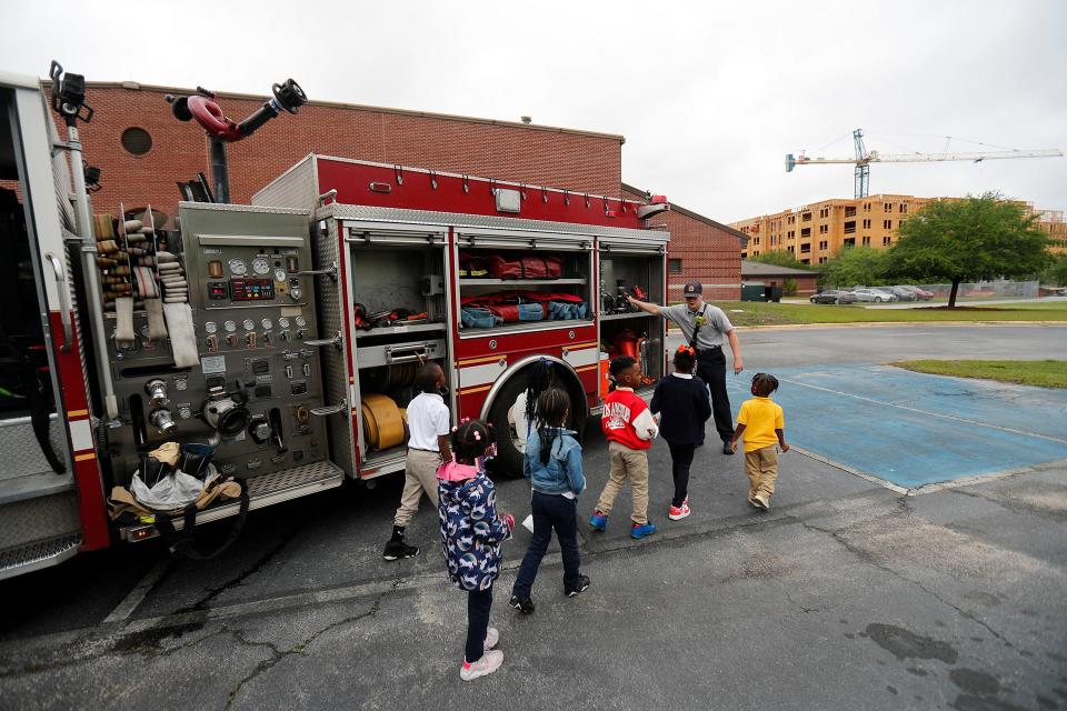 Firefighter shows children the equipment on the firetruck during a "Touch the Truck" event.