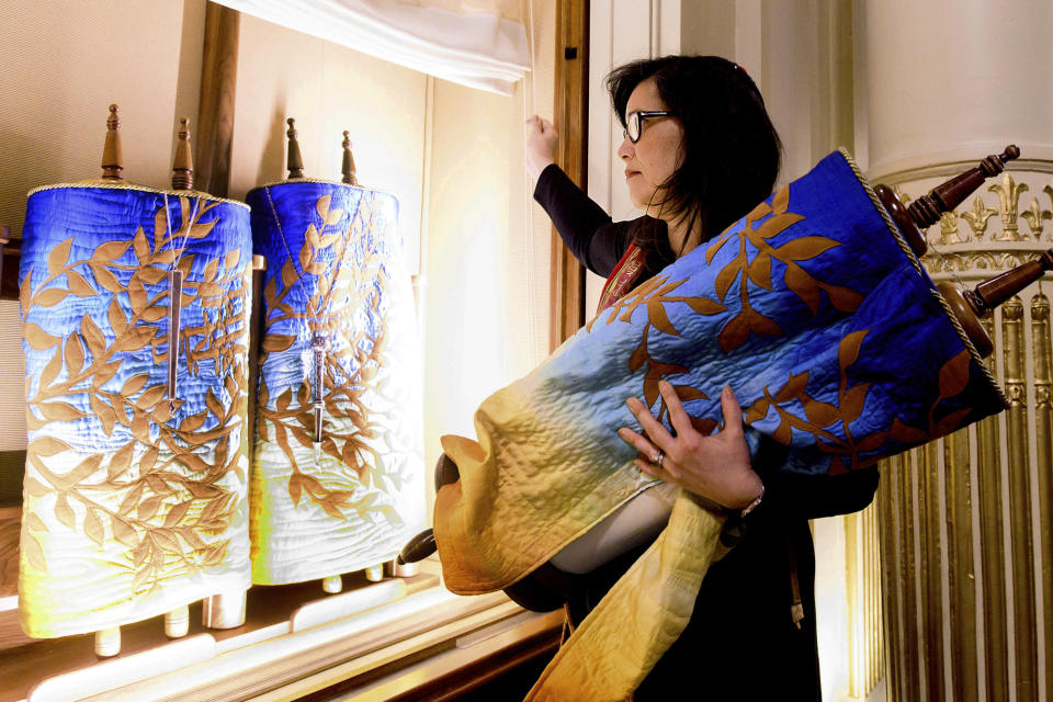 In this Saturday, Feb. 1, 2020, photo, Rabbi Jacqueline Mates-Muchin removes a Torah scroll from the ark, a cabinet that houses scrolls of the Hebrew Bible, while preparing for Shabbat morning service at Temple Sinai in Oakland, Calif. In September 2017, on the first day of Rosh Hoshana, the Jewish new year, a security guard found an anti-Semitic message scrawled on an outdoor wall of Temple Sinai. “Since 2017, the congregation has been looking to try to feel safe,” she said. “It’s another layer that we always have to be conscious of.” (AP Photo/Noah Berger)