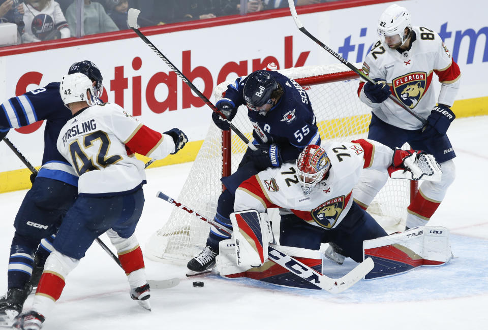 Winnipeg Jets' Mark Scheifele (55) crashes into Florida Panthers goaltender Sergei Bobrovsky (72) as Panthers' Kevin Stenlund (82) defends during third-period NHL hockey game action in Winnipeg, Manitoba, Saturday, Oct. 14, 2023. (John Woods/The Canadian Press via AP)