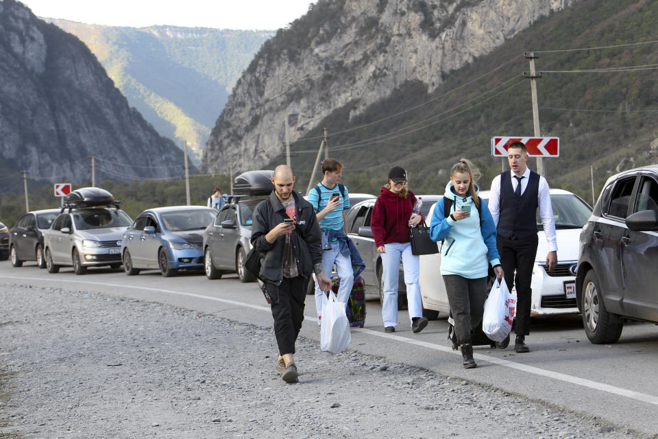 People walk toward the border crossing at Verkhny Lars between Georgia, bottom, and Russia leaving Chmi, North Ossetia–Alania Republic, Russia, Wednesday, Sept. 28, 2022. Long lines of vehicles have formed at a border crossing between Russia's North Ossetia region and Georgia after Moscow announced a partial military mobilization. A day after President Vladimir Putin ordered a partial mobilization to bolster his troops in Ukraine, many Russians are leaving their homes. (AP Photo)