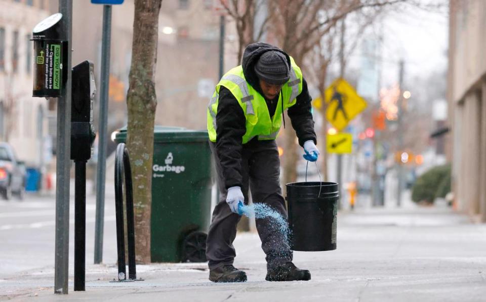 Tyron Brown with Bloomsbury Landscapes spreads ice melt outside Death & Taxes in downtown Raleigh, N.C., Sunday morning January 16, 2022.