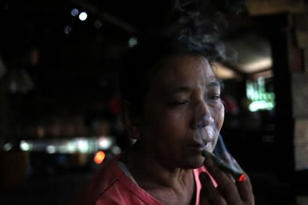 Aung Myint Kyi, who says she was abused by her husband, smokes a cigarette in her home in Dawei