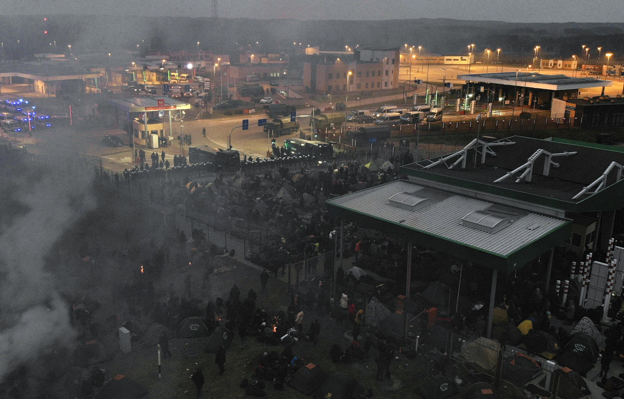 In this image taken with a drone migrants from the Middle East and elsewhere gather at the checkpoint "Kuznitsa" at the Belarus-Poland border near Grodno, Belarus, on Monday, Nov. 15, 2021. The EU is calling for humanitarian aid as up to 4,000 migrants are stuck in makeshift camps in freezing weather in Belarus while Poland has reinforced its border with 15,000 soldiers, in addition to border guards and police. (Leonid Shcheglov/BelTA via AP)