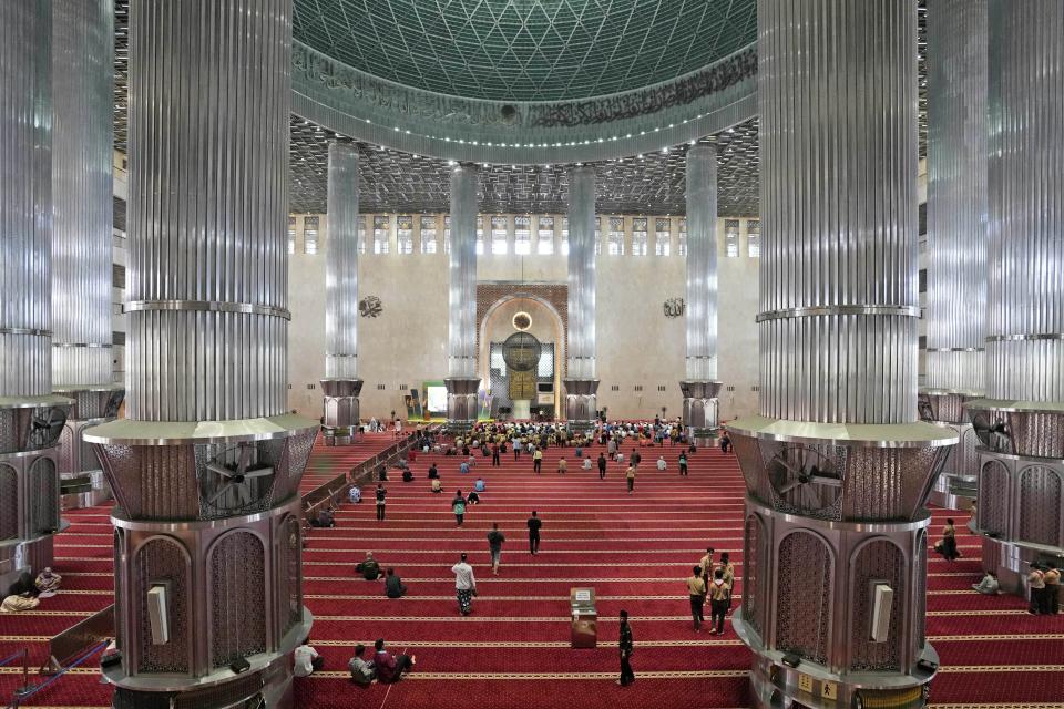 People arrive for midday prayer at Istiqlal Mosque whose electricity partially come from solar power, in Jakarta, Indonesia, Wednesday, March 29, 2023. A major renovation in 2019 installed upwards of 500 solar panels on the mosque's expansive roof, now a major and clean source of Istiqlal's electricity. (AP Photo/Tatan Syuflana)