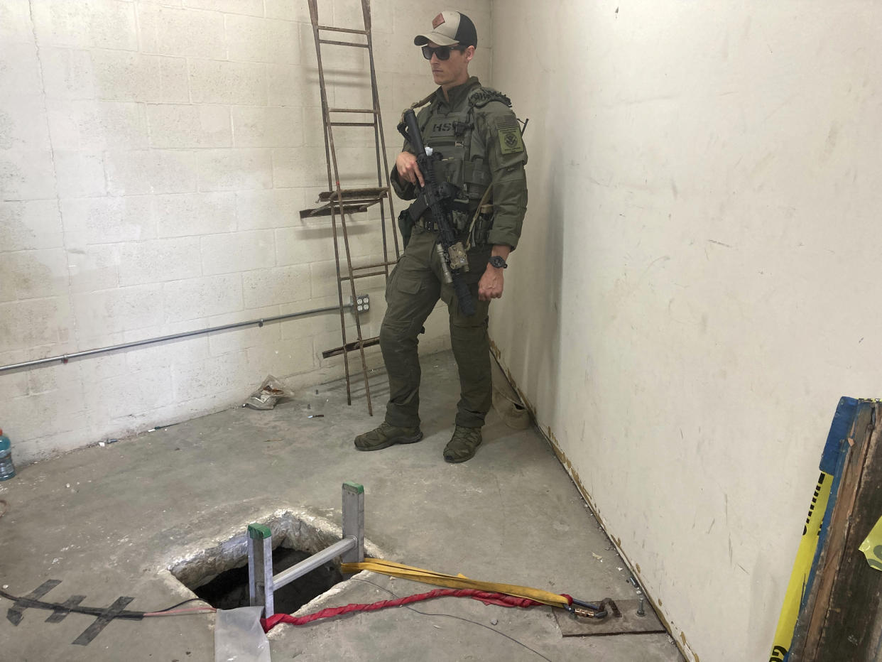 A law enforcement officer stands by the opening of a cross-border tunnel on Monday, May 16, 2022 between Mexico's Tijuana into the San Diego area. Authorities have announced the discovery of the underground smuggling tunnel on Mexico's border, running the length of a football field on U.S. soil to a warehouse in an industrial area. The cross-border tunnel from Tijuana to the San Diego area was built in one of the most fortified stretches of the border, illustrating the limitations of former President Donald Trump's border wall. (AP Photo/Elliot Spagat)