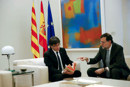 Catalan President Carles Puigdemont (L) browses through a facsimile of the second of part of Spanish writer Miguel de Cervantes' famous novel "Don Quijote" (Don Quixote) given to him by Spanish acting Prime Minister Mariano Rajoy (R) at the Moncloa Palace in Madrid, Spain, April 20, 2016. REUTERS/Susana Vera