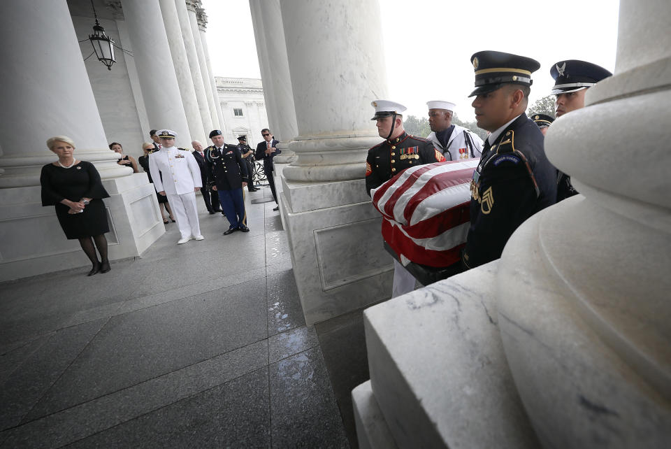 Cindy McCain (left) watches as a military honor guard team carries the flag-draped casket.