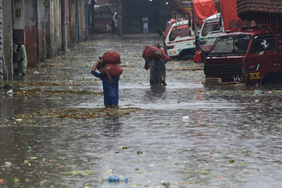 Workers carry sacks of onions in a flooded market after a heavy rain shower in Lahore on July 14, 2022.<span class="copyright">Arif Ali—AFP/Getty Images</span>