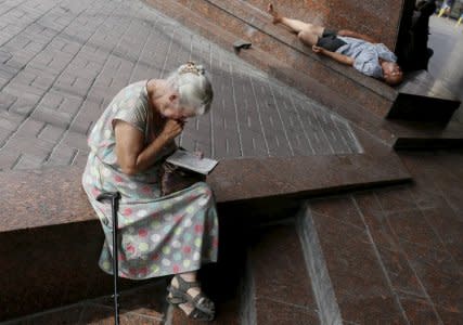 FILE PHOTO: An elderly woman works on a crossword puzzle as she rests in the shade in central Kiev, Ukraine, July 20, 2015.  REUTERS/Gleb Garanich